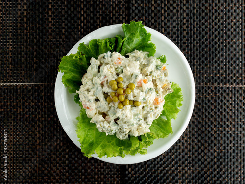 top view of olivier salad bowl garnished with lettuce