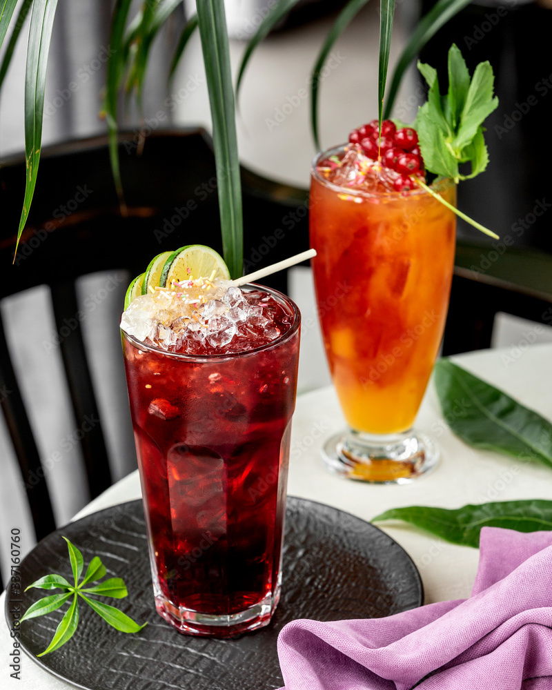 two glasses of cocktails garnished with lime and redcurrant two glasses of cocktails garnished with lime and redcurrant