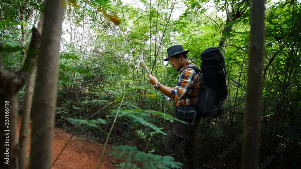 man traveler with backpack and map searching directions in the natural forest man traveler with backpack and map searching directions in the natural forest