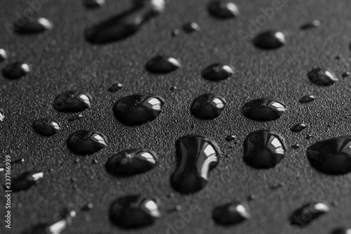 Water drops on black metal surface. 