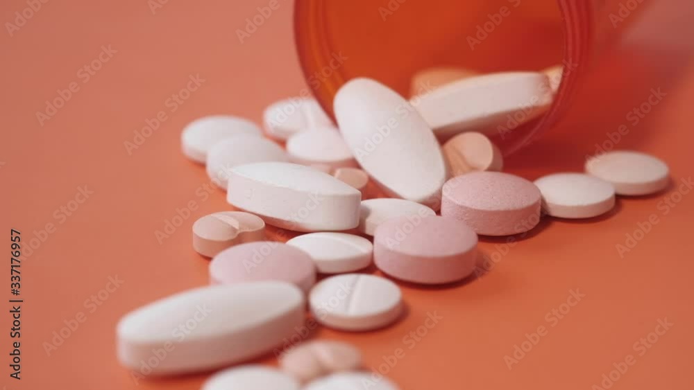 white pills spilling from container, top view white pills spilling from container, top view