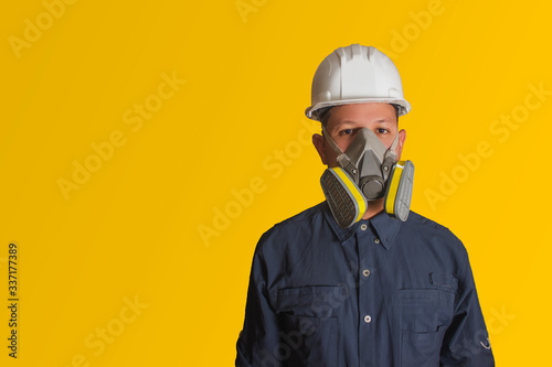 Cuadro en lienzo Hombre hispano con mascarilla y casco blanco de seguridad en fondo amarillo