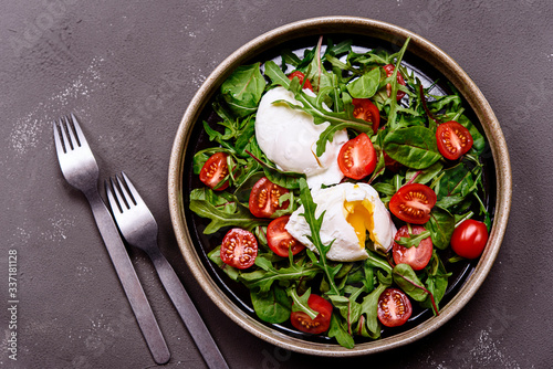Cherry Tomatoes, poached eggs and herbs mix salad on dark background. Simple and healthy nutrition. Selective focus