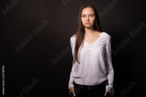 Beautiful girl with long straight hair stands straight, looks directly at camera