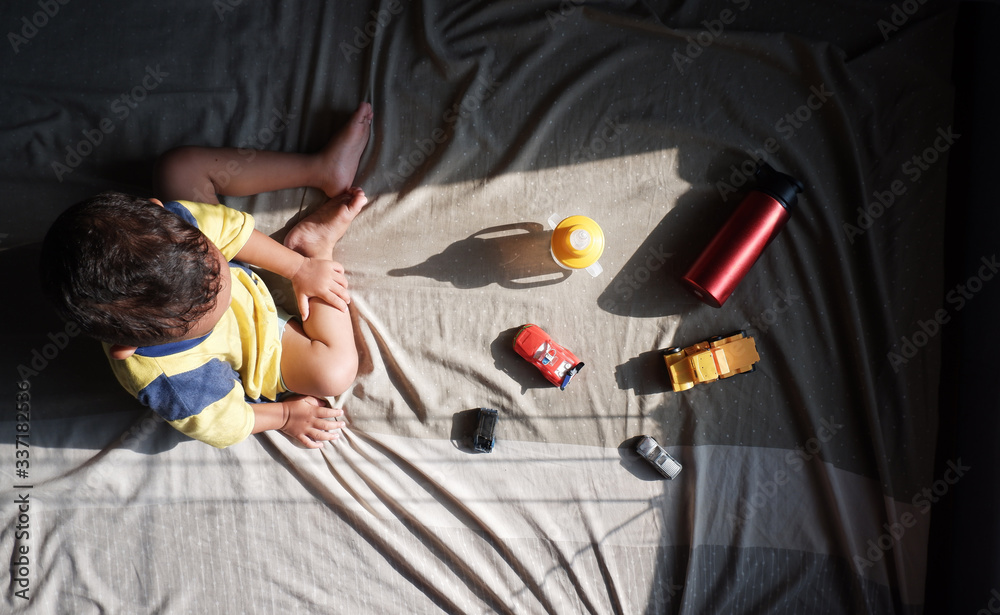 high angle view of kid playing toys on the bed while sunbathing in the morning