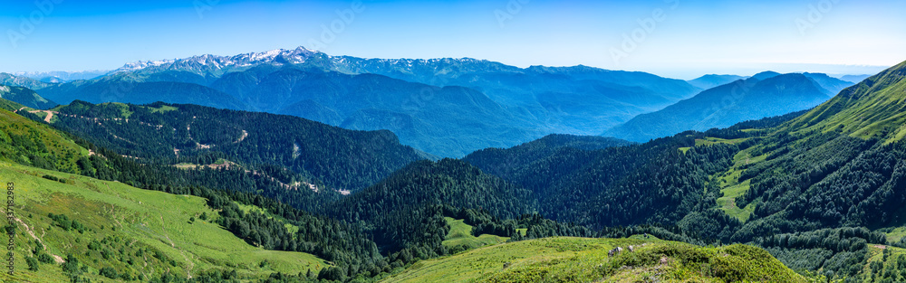 Obraz premium Panoramic view over the Green Valley, surrounded by high mountains with snow on a clear summer day.
