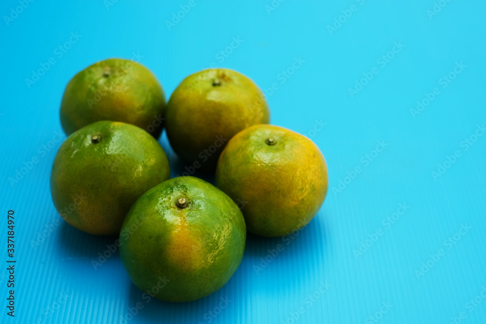 Green orange fruits on blue background Green orange fruits on blue background