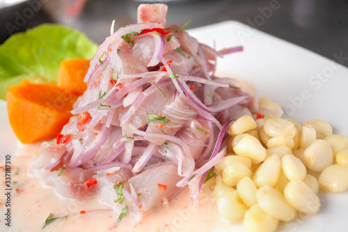 Peruvian seafood: fish cebiche with onion, chili, sweet corn and sweet potato served on a white plate photo