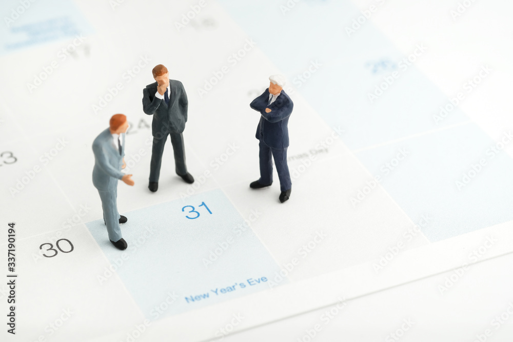 Miniature people : A group of businessmen standing on the white calendar and look at the end of new year (31 Dec) with copy space. He plan the new strategy for next year. Business, finance and concept Miniature people : A group of businessmen standing on the white calendar and look at the end of new year (31 Dec) with copy space. He plan the new strategy for next year. Business, finance and concept