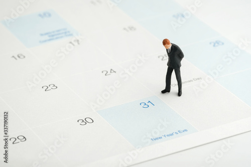 Miniature people : Businessmen standing on the white calendar and look at the end of new year (31 Dec) with copy space. He plan the new strategy for next year. Business, finance and holiday concept.