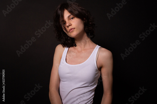 Young woman calmly looking at camera and posing for photoshoot. Black background