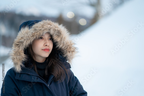 Portrait of woman wearing warm coat with fur hood, having fun in winter © marchsirawit