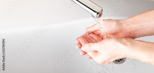  Washing hands under a stream of water in the bathroom over the sink. Close-up of men's hands. Panoramic banner background.
