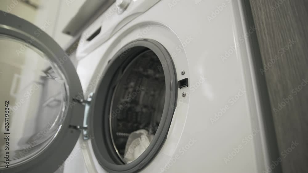 Female hands trys to open laundry machine and takes White CLOTHES. Loading washing machine. Load clothes to washer machine. Load clothes laundry washing machine Female hands trys to open laundry machine and takes White CLOTHES. Loading washing machine. Load clothes to washer machine. Load clothes laundry washing machine