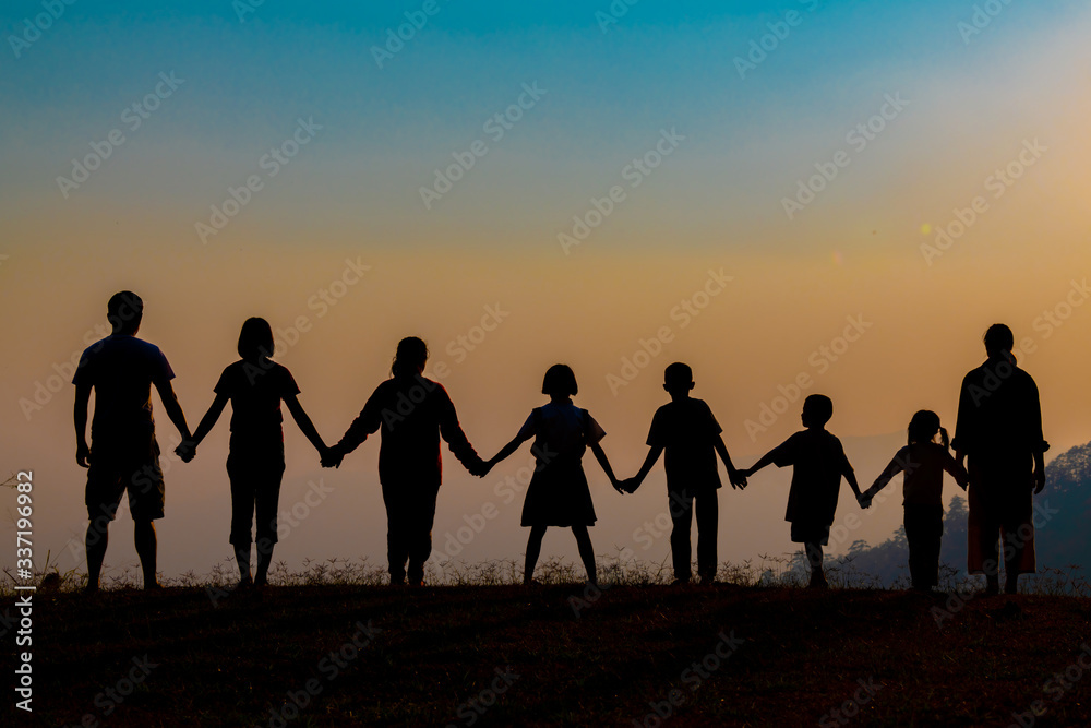 The shadow of a happy family holding hands in the meadow during sunset Happy family enjoying life together outdoors Round dance celebration ceremony