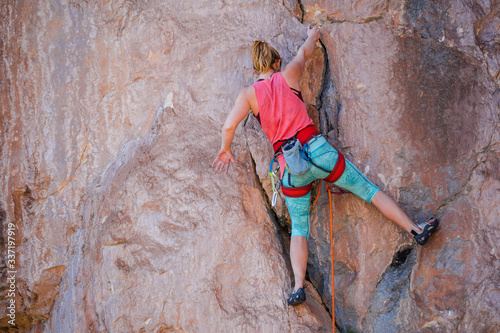 Fototapeta Naklejka Na Ścianę i Meble -  A girl climbs a rock.