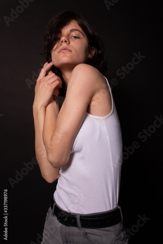 Young woman with short hair dark eyes posing for photoshoot. Black background