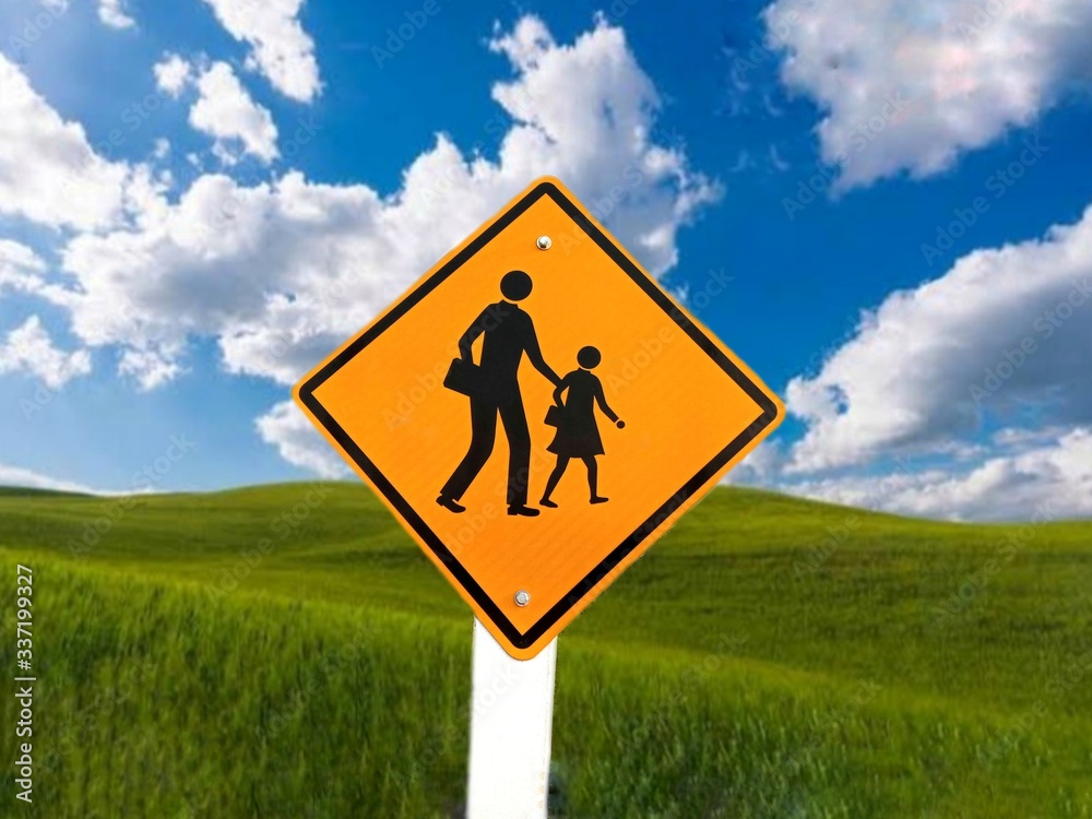 School zone warning yellow traffic road sign isolated on blue sky background closeup. School zone warning yellow traffic road sign isolated on blue sky background closeup.