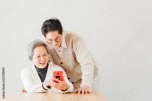 Asian aged couple at home using a smartphone photo