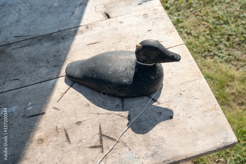 Wooden duck decoy for hunters stands on a table, on a background of grass. photo