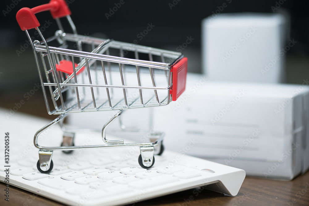Red trolley on laptop keyboard.A cart and box product for send to customer .Electronic commerce that allows consumers to directly buy goods from a seller over the internet.Shopping online concept.