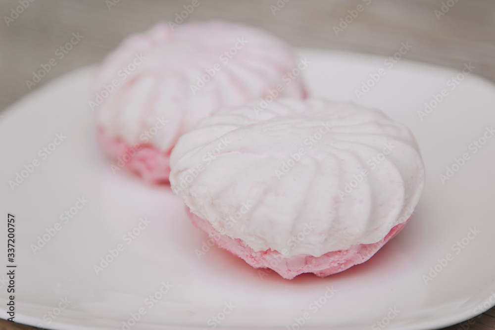 White plate with pink marshmallows on a light table. gastritis dessert White plate with pink marshmallows on a light table. gastritis dessert