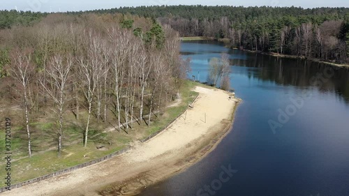 Drone flight over the sandy beach of a small dam in the heath, aerial view POV photo
