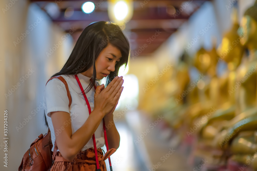 Woman traveller pay gentle respect to the buddha statue in the temple, praying respect for a better life forward Woman traveller pay gentle respect to the buddha statue in the temple, praying respect for a better life forward