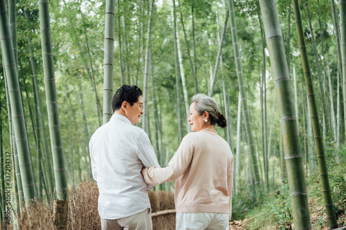Asian aged couple walking in the bamboo forest photo