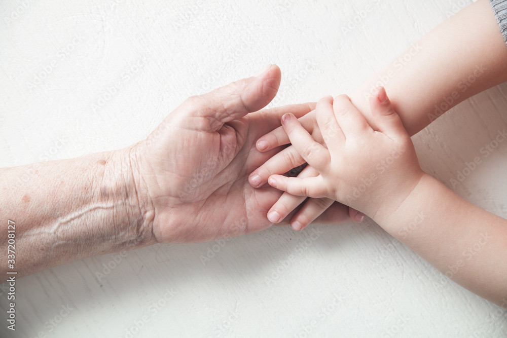 Fototapeta premium Elderly woman and a kid hands together.