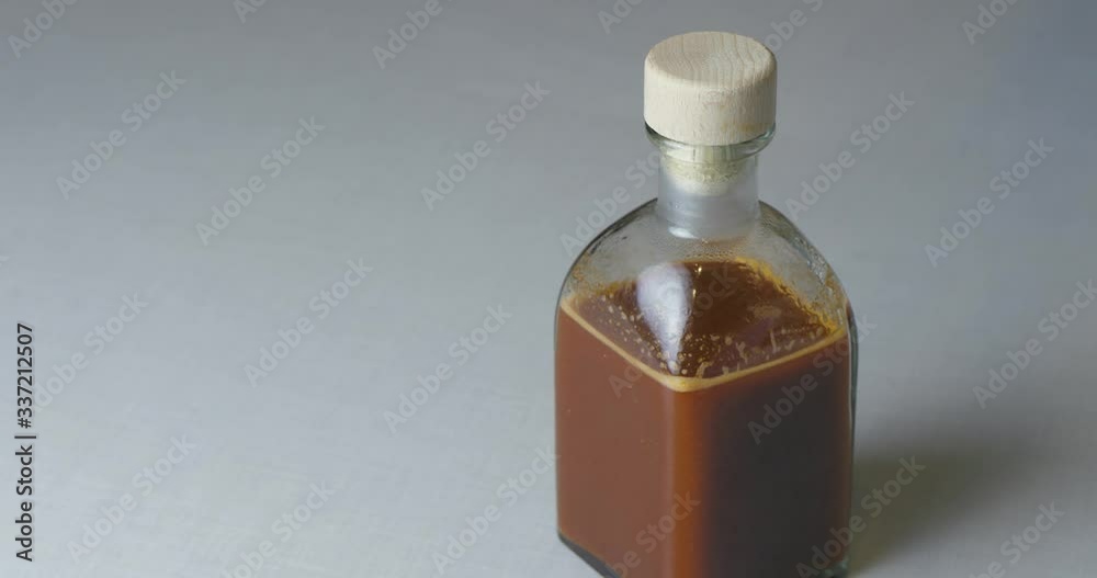 The Cook Closes The Glass Bottle With A Wooden Cork In Which A Freshly Cooked Spicy Red Chili Sauce. Vegetable Stew In A Pan. Close-up / Cinema 4K The Cook Closes The Glass Bottle With A Wooden Cork In Which A Freshly Cooked Spicy Red Chili Sauce. Vegetable Stew In A Pan. Close-up / Cinema 4K