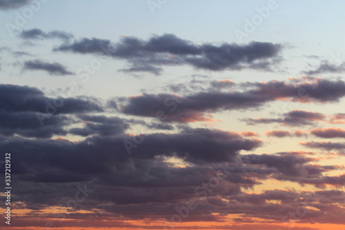 Clouds in the blue sky at sunset or dawn backlit by the sun. Place for text and design.