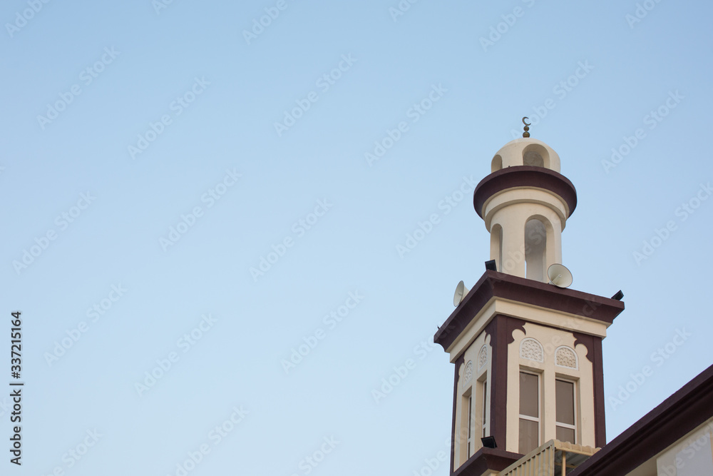 A mosque minaret against clear blue sky your text on right side
