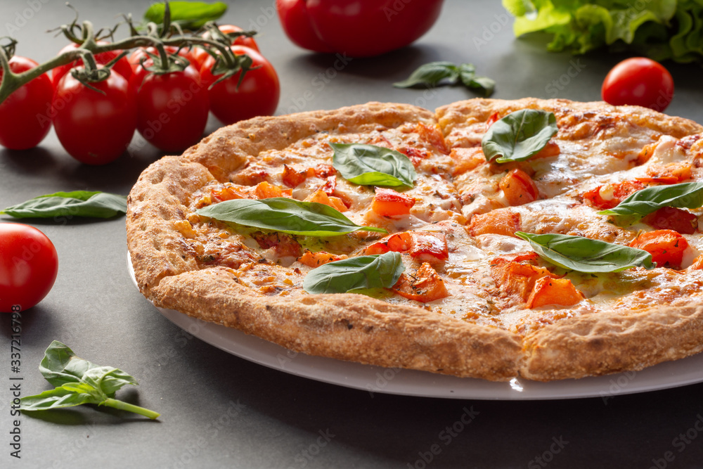 Pizza Margarita on a black background with tomatoes and mozzarella. Still-life. Pizza Margarita on a black background with tomatoes and mozzarella. Still-life.