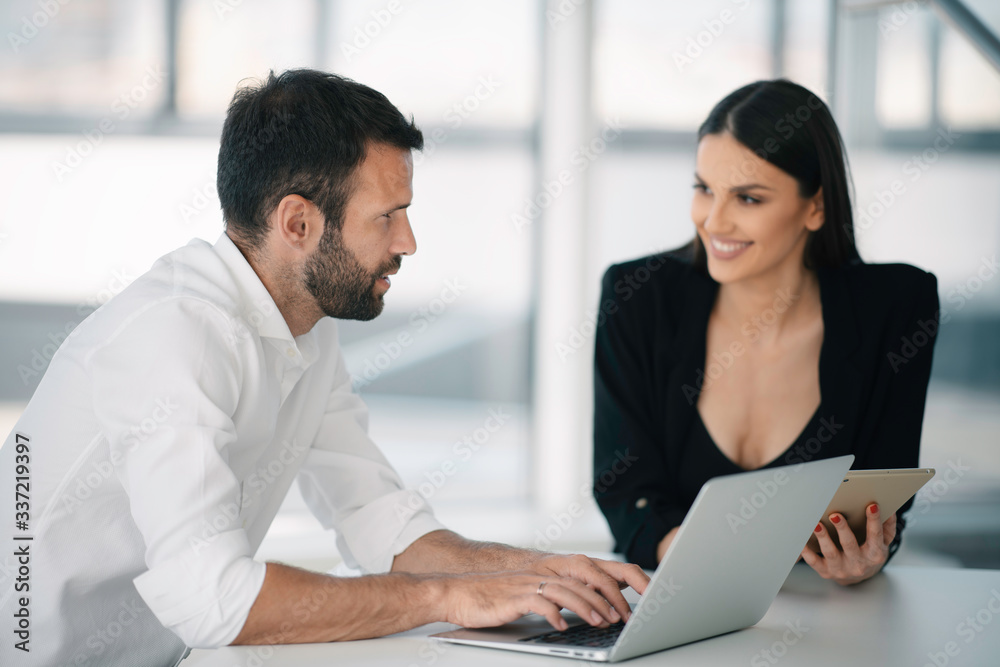 Colleagues working together in office. Young businessman and businesswoman working on project. Colleagues working together in office. Young businessman and businesswoman working on project.
