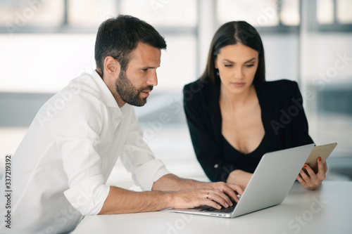 Colleagues working together in office. Young businessman and businesswoman working on project. 