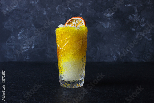 Bright, summer refreshing drink in a tall glass with crushed ice on a dark background. Top view with copy space.
