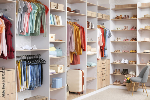 Big wardrobe with different clothes and accessories in dressing room photo