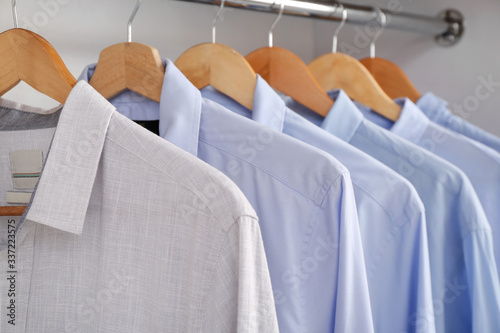 Stylish male clothes on hanger in wardrobe