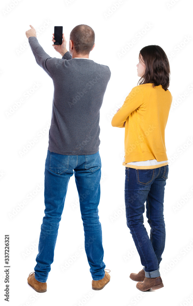 Fototapeta premium Back view of couple in sweater with mobile phone.