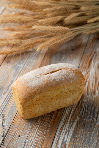 A loaf of white wheat bread on old wooden background