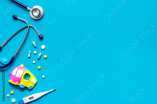 Flu treatment for children. Pills  thermometer  stethoscope and toys on blue background top view copy space