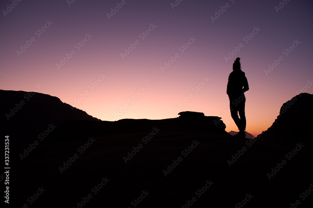 Woman watching sunrise in Wadi Rum desert, Jordan