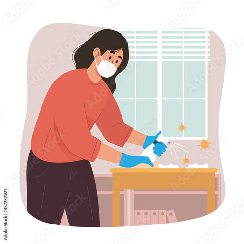 Young woman cleaning table with disinfectant spray