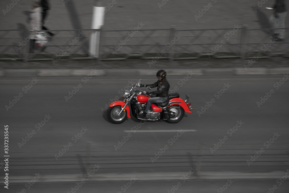 motorcyclist driving on red motorcycle on the city street. Biker on red chopper riding on empty street with motion blur effect.