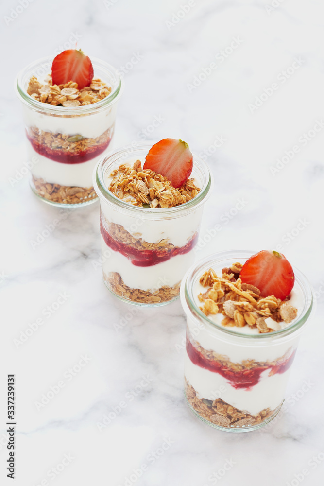 Small jars of granola with yogurt-strawberry jam and fresh strawberries. Small jars of granola with yogurt-strawberry jam and fresh strawberries.