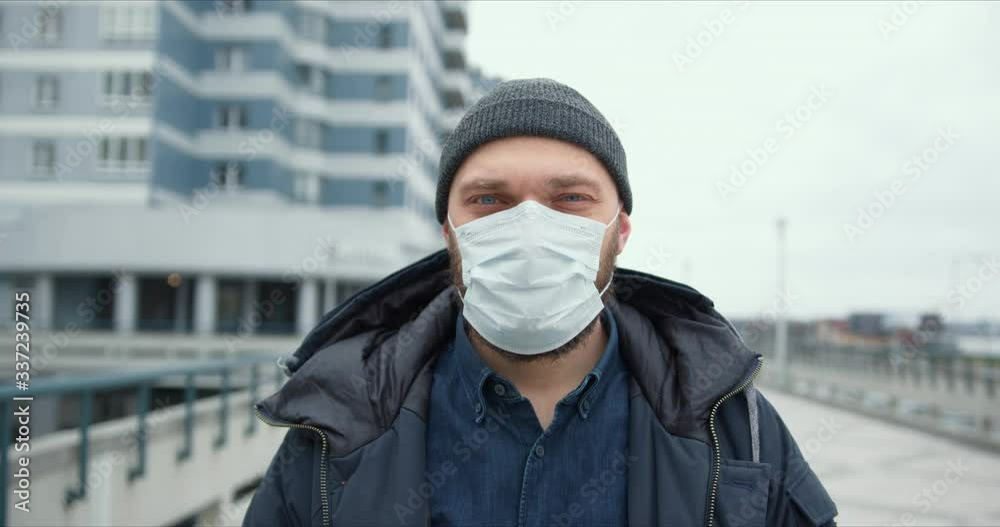 Epidemic protection. Portrait of young bearded Caucasian man wearing medical mask outdoors during coronavirus quarantine Epidemic protection. Portrait of young bearded Caucasian man wearing medical mask outdoors during coronavirus quarantine