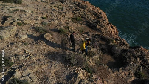 Aerial photography of rocks near the sea. Father and son are standing on the edge of a cliff. Around the drone around people. photo