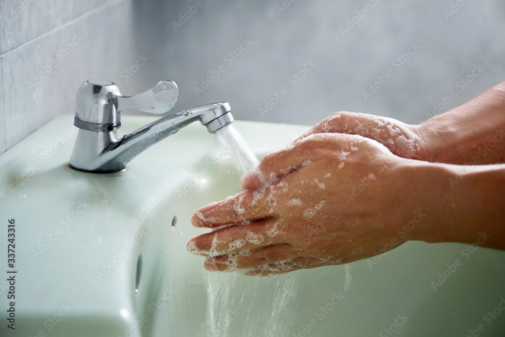Fototapeta premium Washing of hands with soap under the crane with water