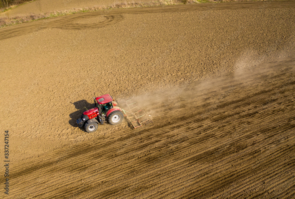aerial shot of Farmer in tractor preparing land with seedbed cultivator, morning sun 